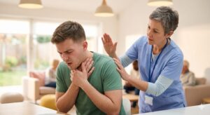 誤嚥した男性の詰まったものを出すのに、女性が背中を叩きださせてあげている写真